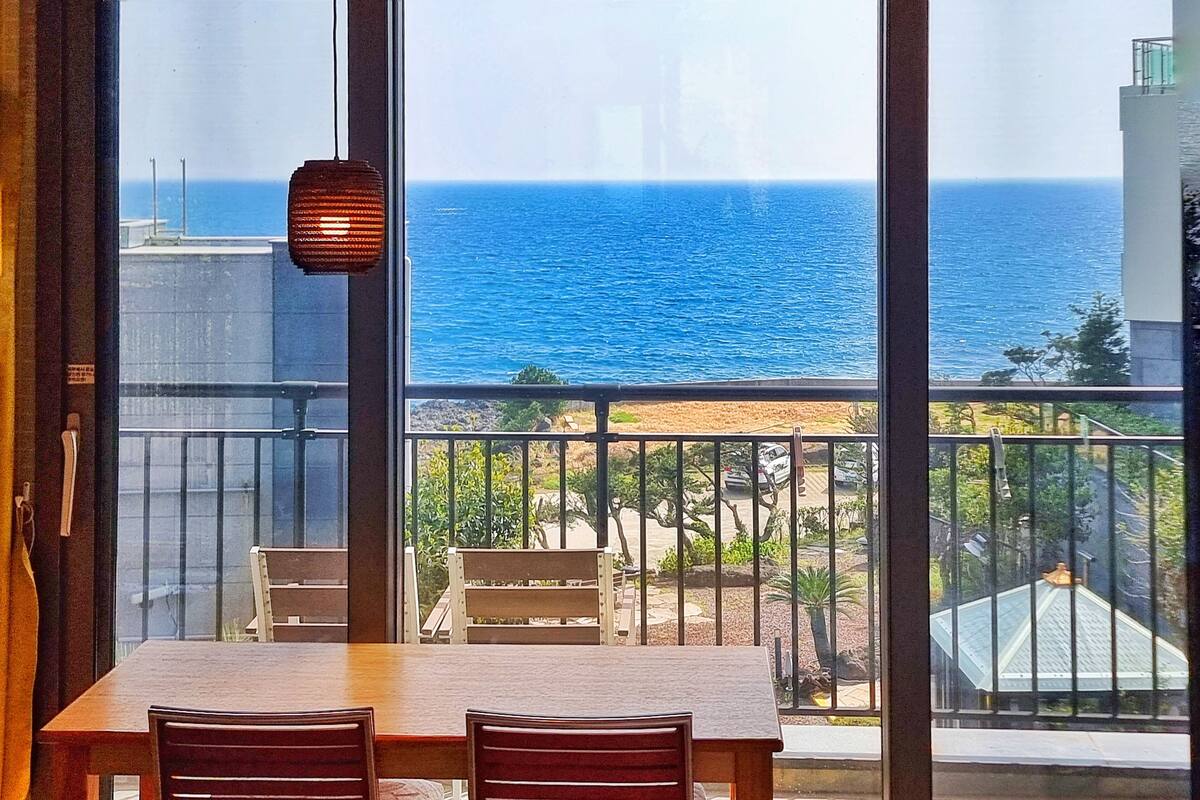 A dining area with a view of the ocean through large windows.