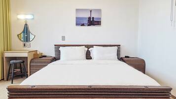 A hotel room with a bed, bedside tables, a desk, a chair, a mirror, and a picture on the wall.