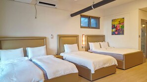 Habitación de hotel con tres camas, una ventana, un cuadro y un equipo de aire acondicionado.