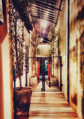 A narrow corridor with wooden flooring, metal railings, and potted plants. - The Roo Classic Hometel (Songkhla)