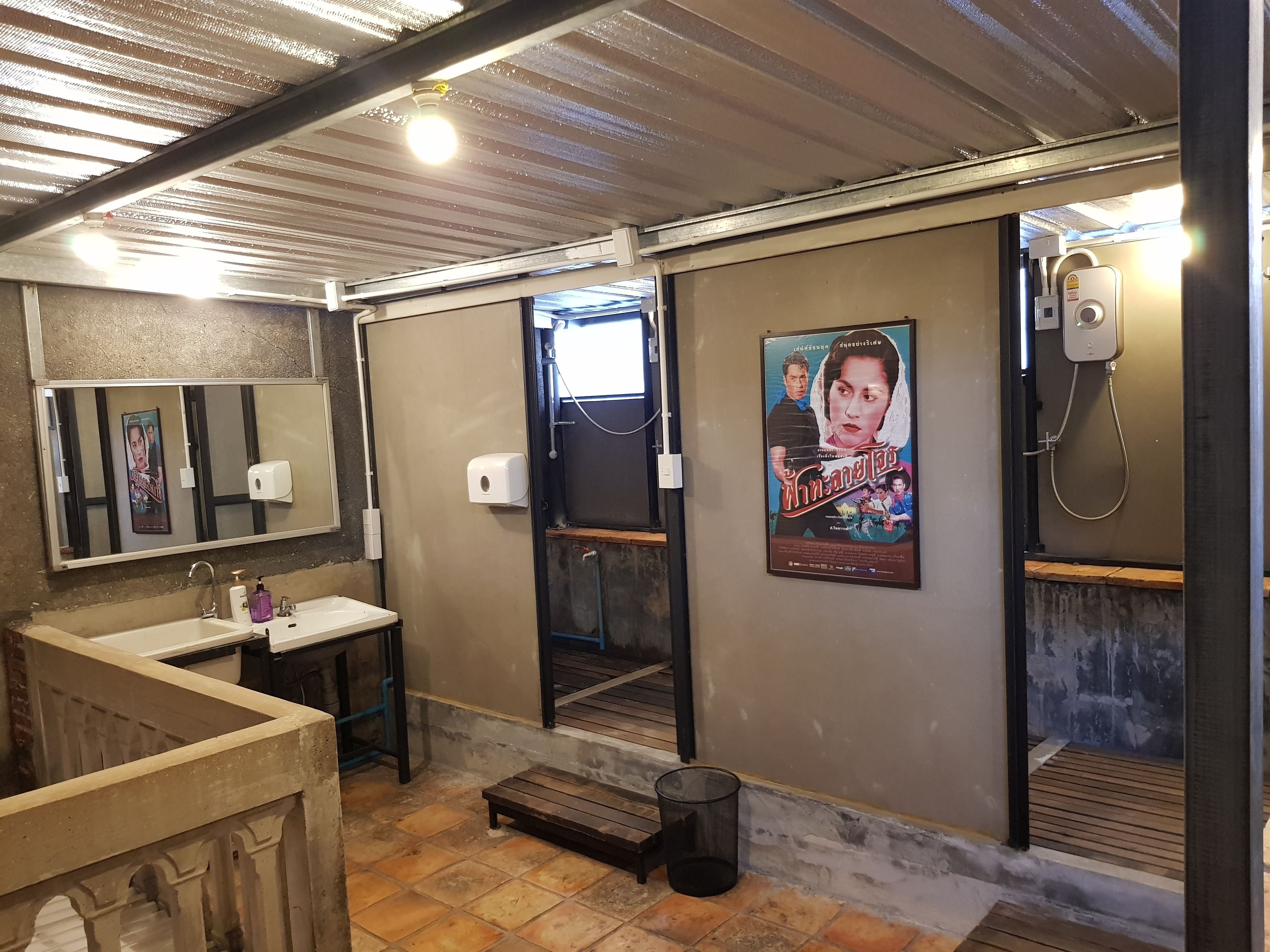 Un baño con lavamanos, espejo, cartel y zona de ducha.