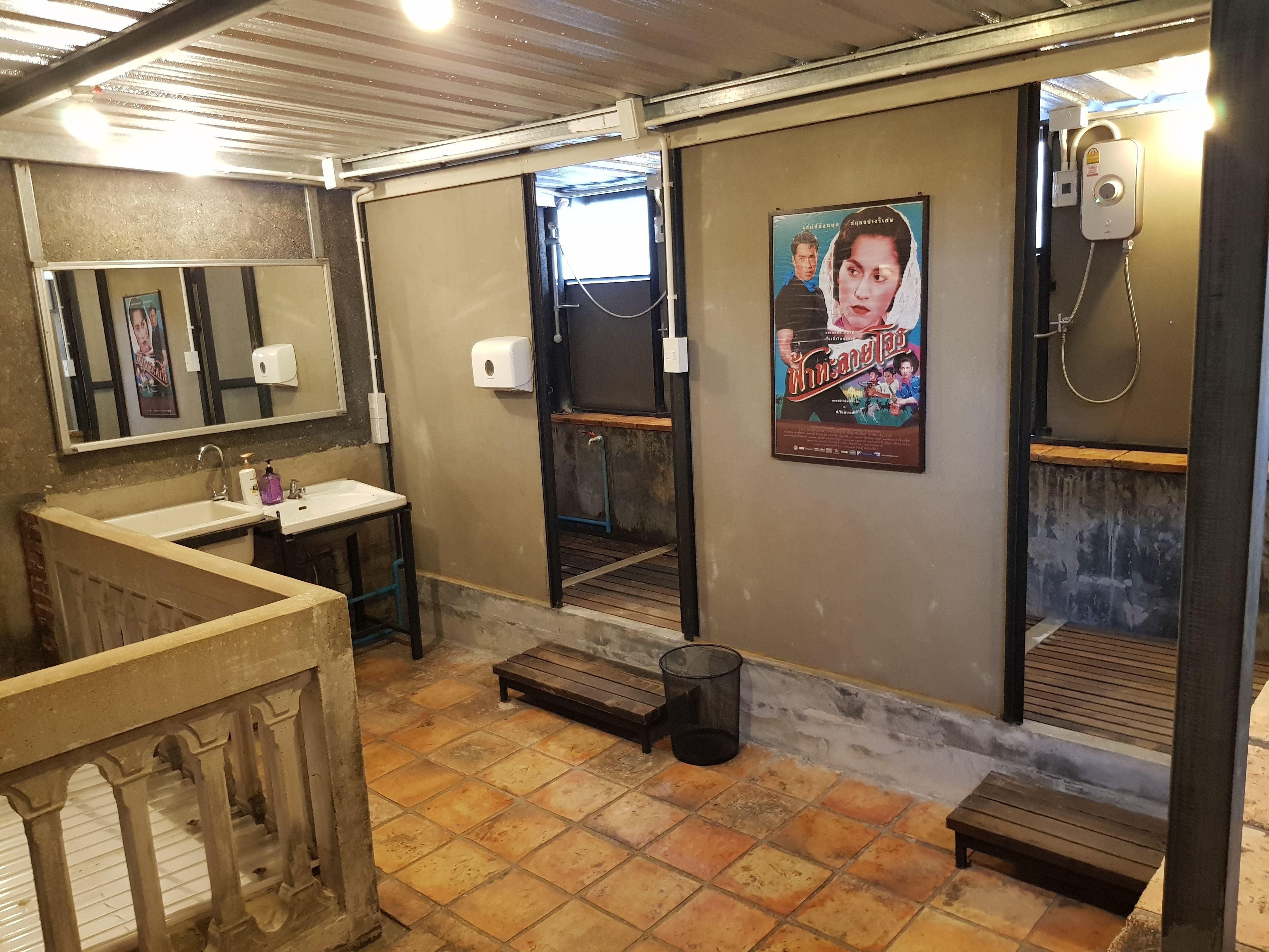 Baño público con lavamanos, espejo y cartel en la pared.
