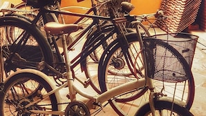 Bicycles parked indoors with a yellow wall and a mural in the background. - The Roo Classic Hometel (Songkhla)