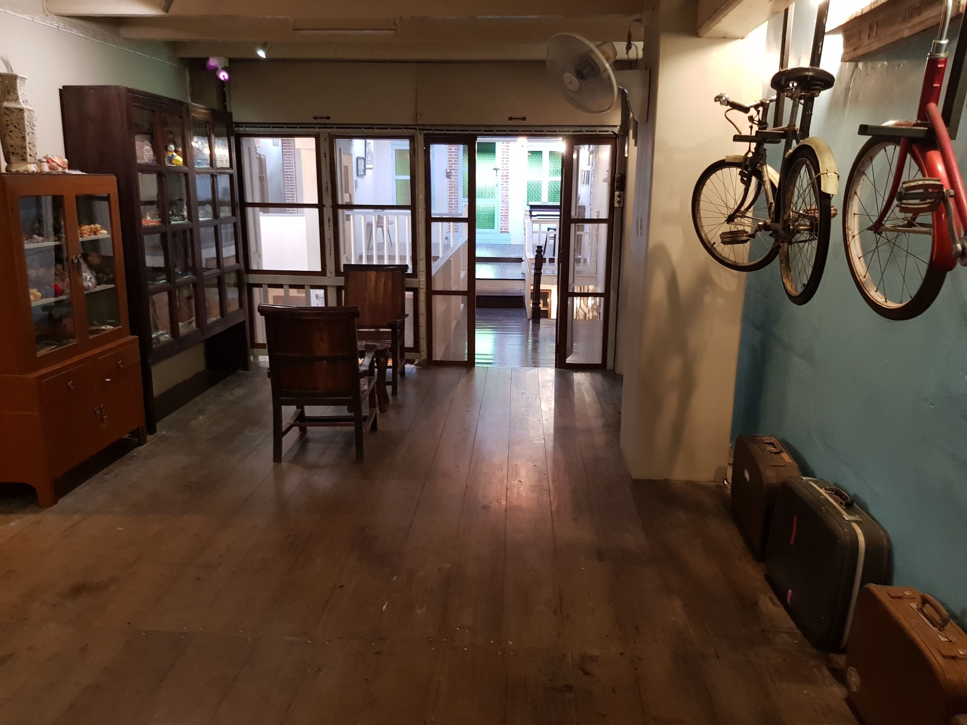 A room with wooden flooring, a dining table with chairs, a cabinet with glass doors, and a bicycle mounted on the wall.
