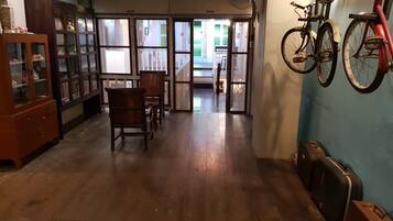 A room with wooden flooring, a dining table with chairs, a cabinet with glass doors, and a bicycle mounted on the wall.