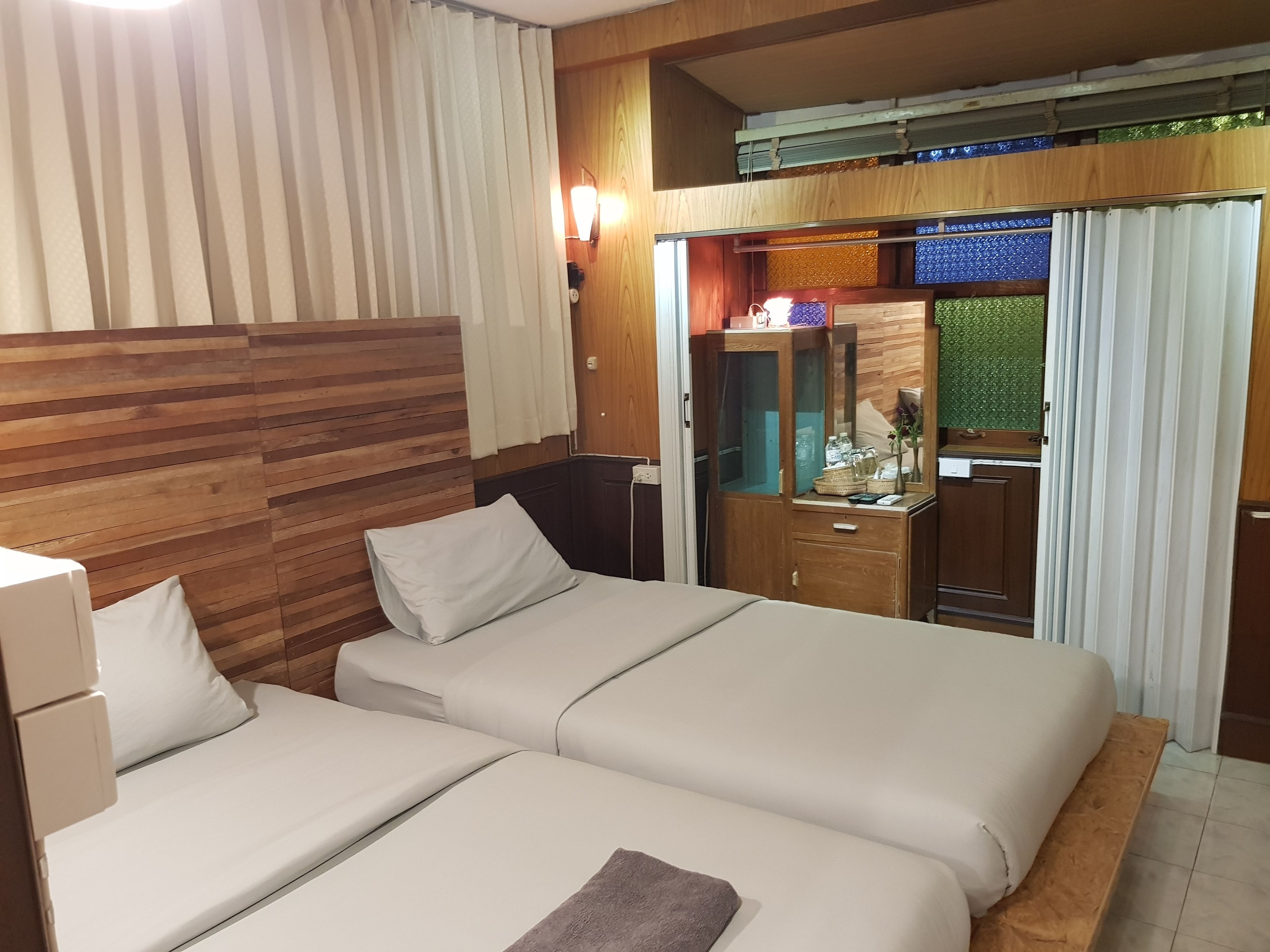 Habitació d'hotel amb dos llits, un capçal de llit de fusta, un escriptori amb un mirall i un armari.