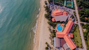 An aerial view of a coastal hotel with a beach, swimming pool, and parking area. - Haad Kaew Resort (Singhanakhon)