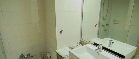 Un baño con inodoro, dos lavamanos, espejo y ducha.