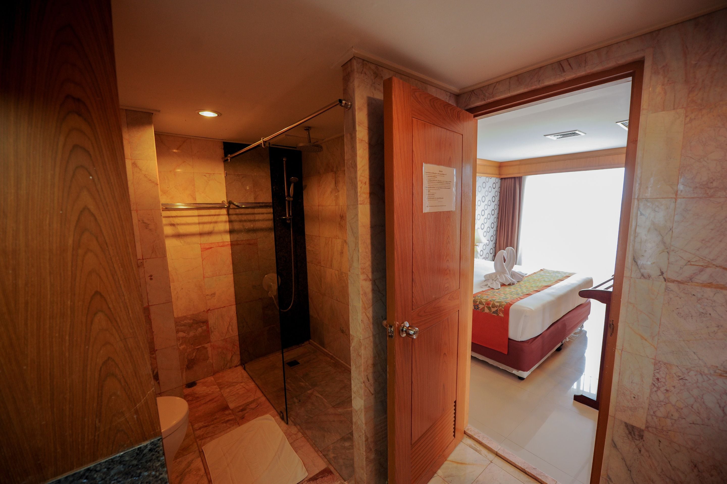 Habitación de hotel con ducha, cama y puerta de madera.