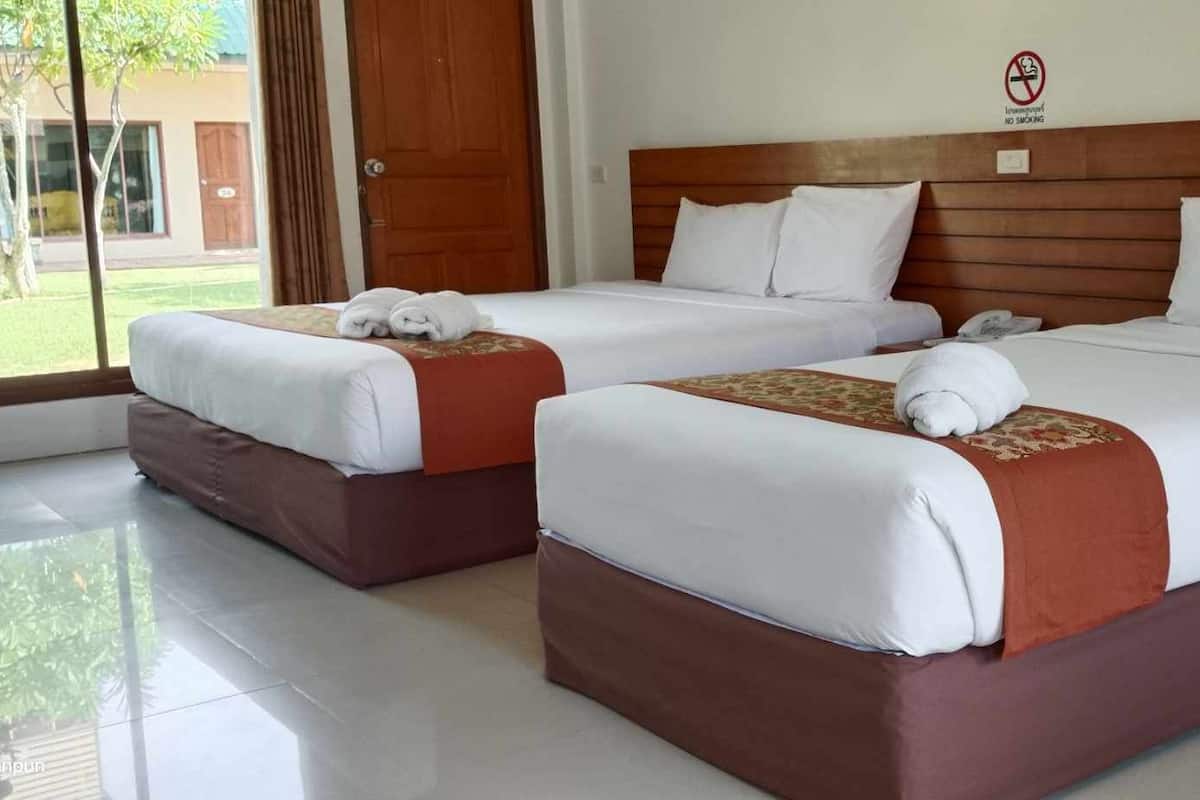 Two double beds with white linens and brown headboards in a hotel room.