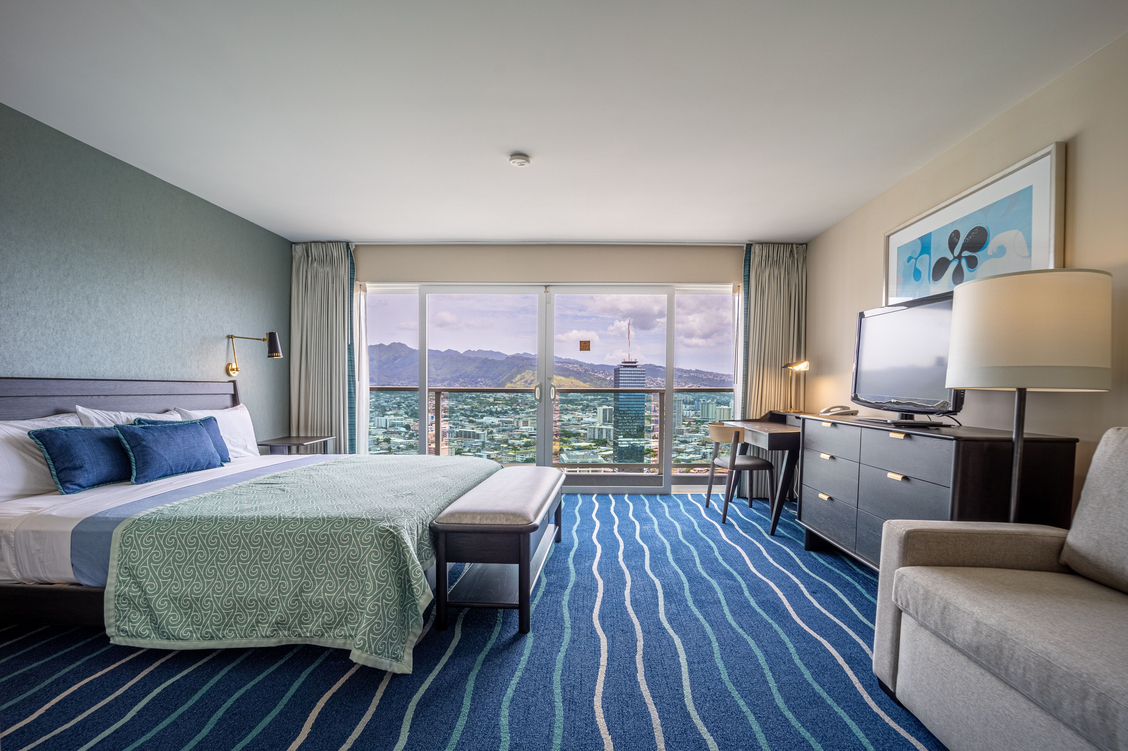 Une chambre d’hôtel avec un grand lit, un bureau, une chaise, une télévision et une vue sur le paysage urbain.