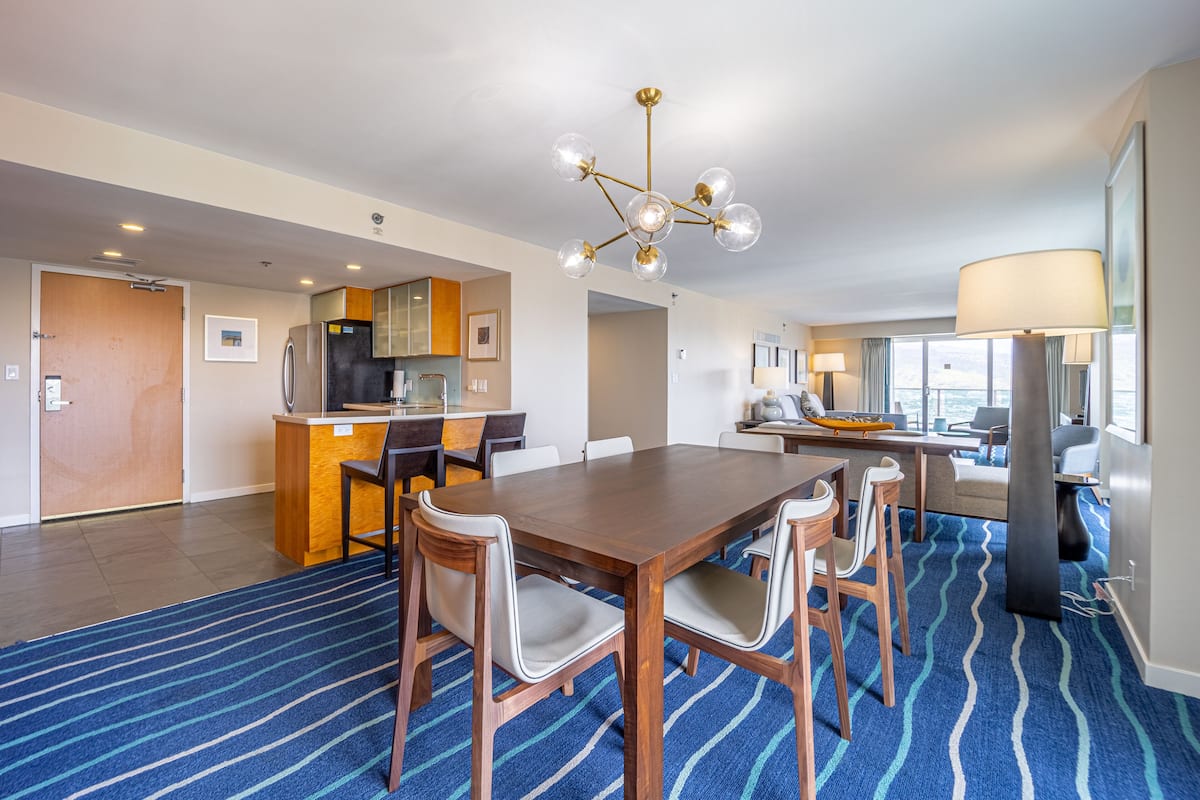 Une chambre d’hôtel avec un coin repas, une kitchenette et une grande fenêtre donnant sur un beau paysage.