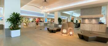 A spacious lobby with a reception desk, seating areas, and a modern chandelier.