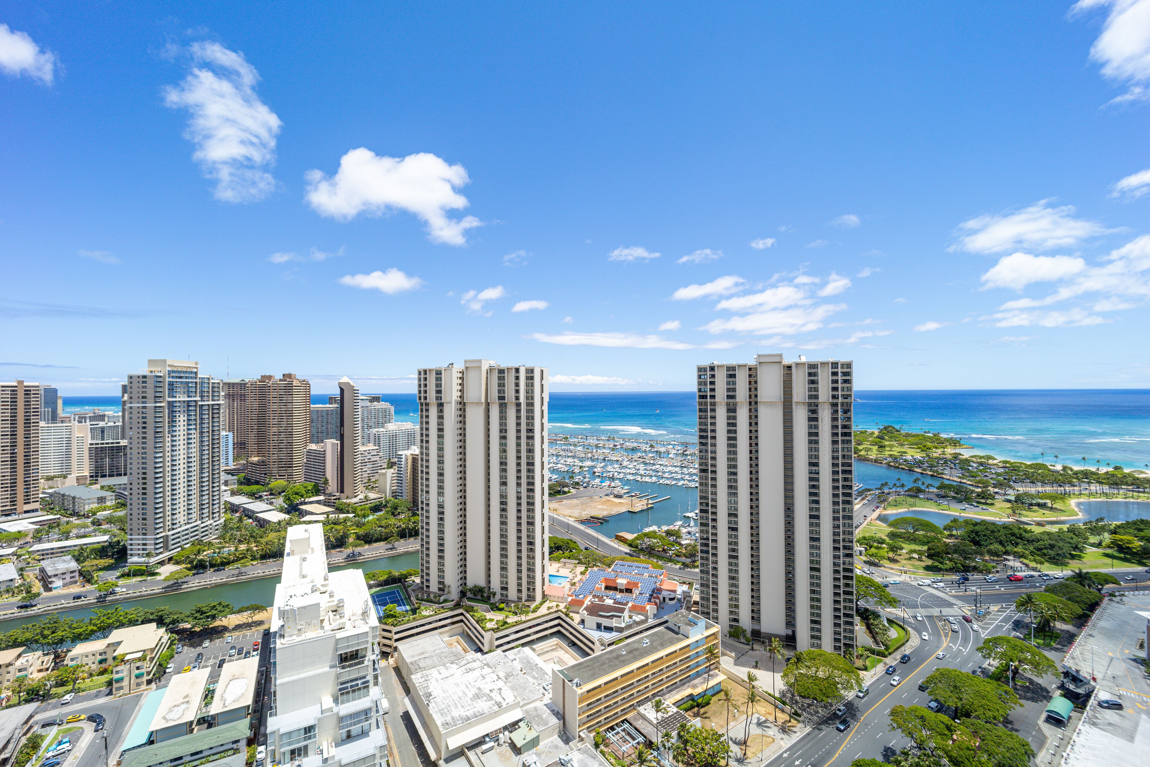 A high-rise urban area with modern buildings, a marina, and a clear blue sky.