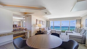 Une chambre d’hôtel moderne dotée d’un coin repas, d’un ensemble de canapés et offrant une vue sur l’océan.