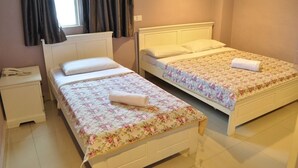 A room with two single beds, each with a floral bedspread and a rolled towel. There is a nightstand with a phone on it, and a window with curtains. - Hotel KK Equine Park (Seri Kembangan)