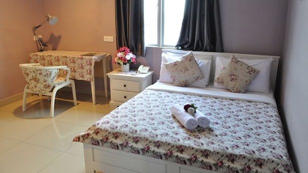 A hotel room with a bed, a desk, a chair, a nightstand, and a window with curtains. - Hotel KK Equine Park (Seri Kembangan)