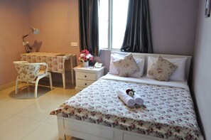 Ein Hotelzimmer mit Bett, Schreibtisch, Stuhl, Nachttisch und einem Fenster mit Vorhängen.
