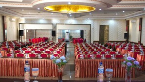 A banquet hall with rows of tables and chairs, equipped with water bottles and glasses, and a large chandelier. - Griya Hotel (Medan)
