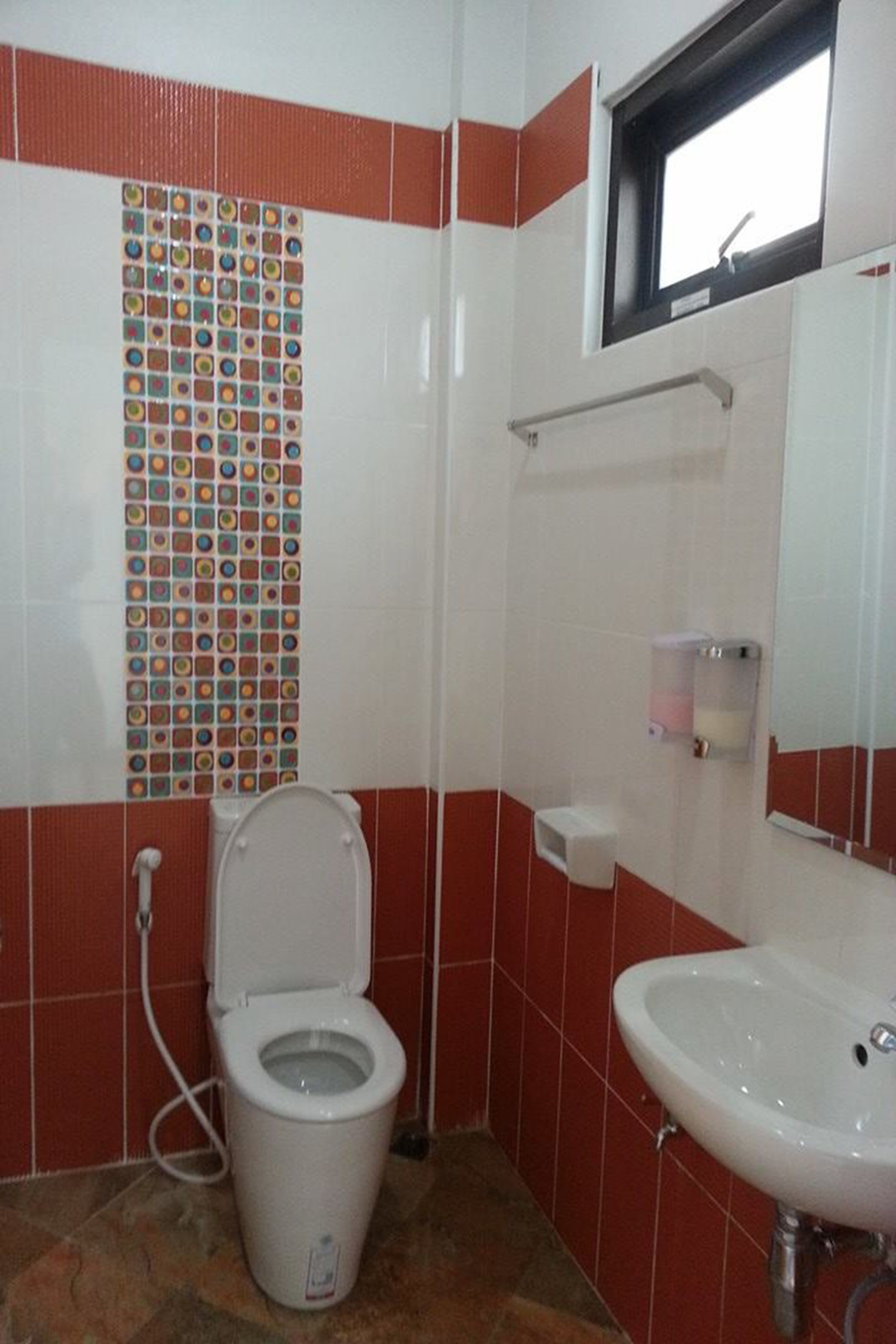 A bathroom with a toilet, sink, and tiled walls.