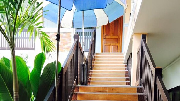Una escalera de madera con peldaños y barandales negros, que conduce a una puerta de madera en la parte superior.