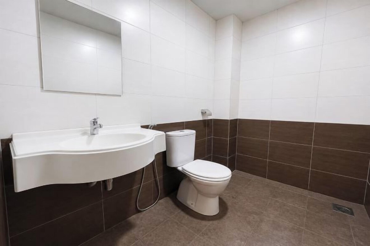 A bathroom with a white sink, a toilet, and brown-tiled walls.