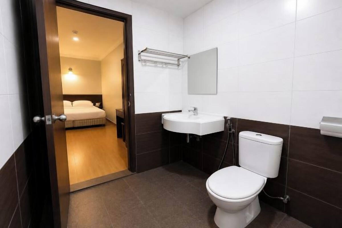 A hotel bathroom with a toilet, sink, and a mirror.