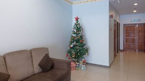 Een hal met een kerstboom, een bruine bank en een deur met de tekst 'KELUAR'.