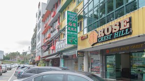 A hotel named Rose Crest Hill with a visible signboard, a multi-story building with balconies, and parked cars along the street. - Hotel Rose Crest Hill, Cameron Highlands (Tanah Rata)
