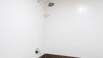 Un baño con azulejos blancos y zona de ducha.