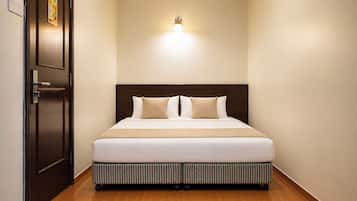 Una camera d'albergo con un letto, una porta e un punto luce a parete.