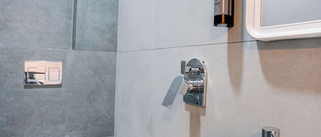 A modern bathroom with a toilet, bidet, sink, and shower.
