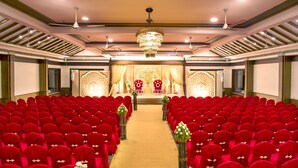 Une grande salle avec des rangées de chaises rouges, une allée centrale et une scène agrémentée de décorations élaborées.