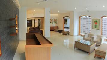 A spacious lobby with a reception desk, seating area, and artwork on the walls.