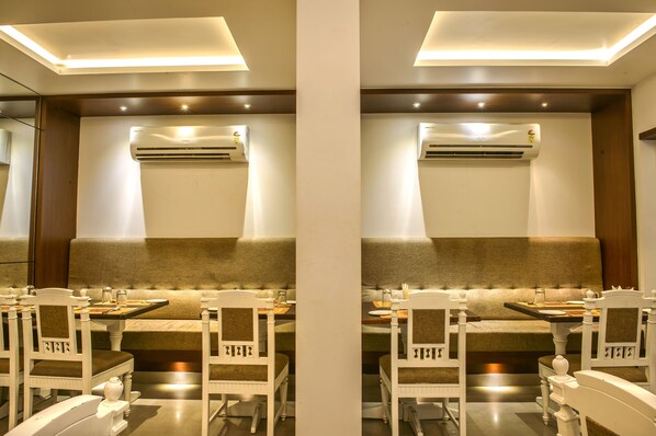 Un comedor con techo alto, iluminación empotrada y una unidad central de aire acondicionado.