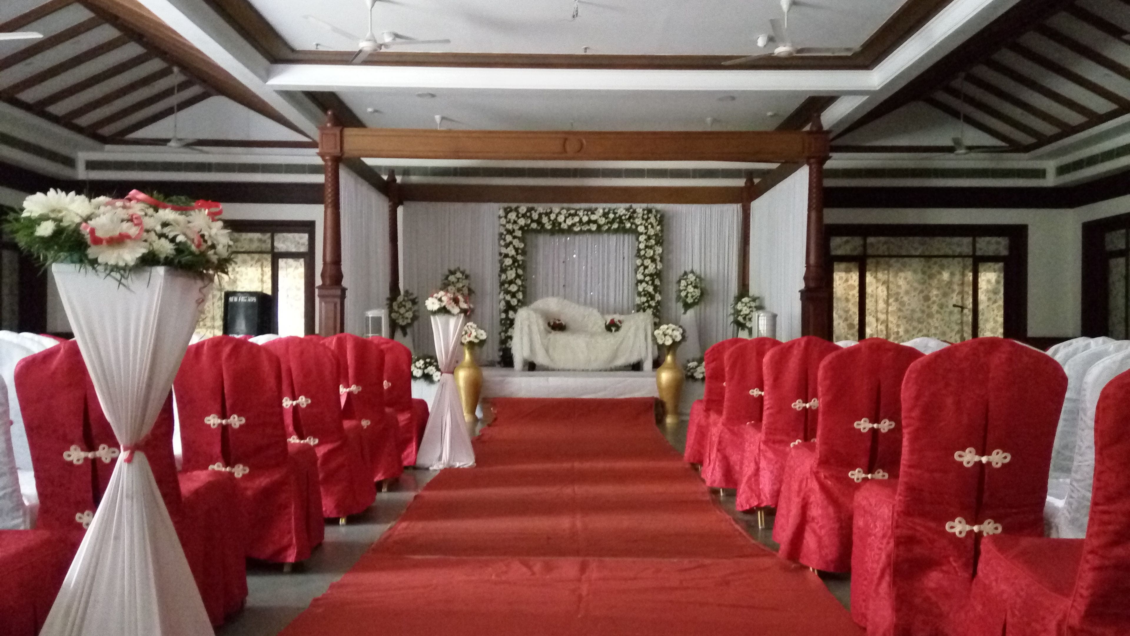 Un pasillo de alfombra roja que conduce a un escenario con decoraciones florales.