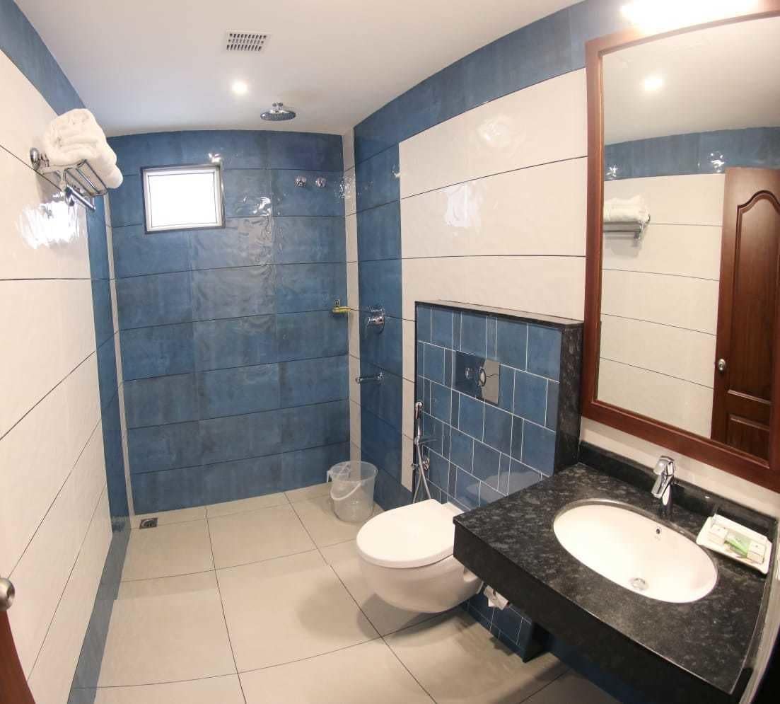 Un baño moderno con un inodoro blanco, un lavamanos con espejo y paredes con azulejos azules.