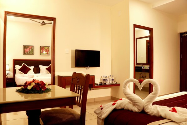 Una habitación de hotel con una cama, un escritorio con silla, un televisor y un espejo.
