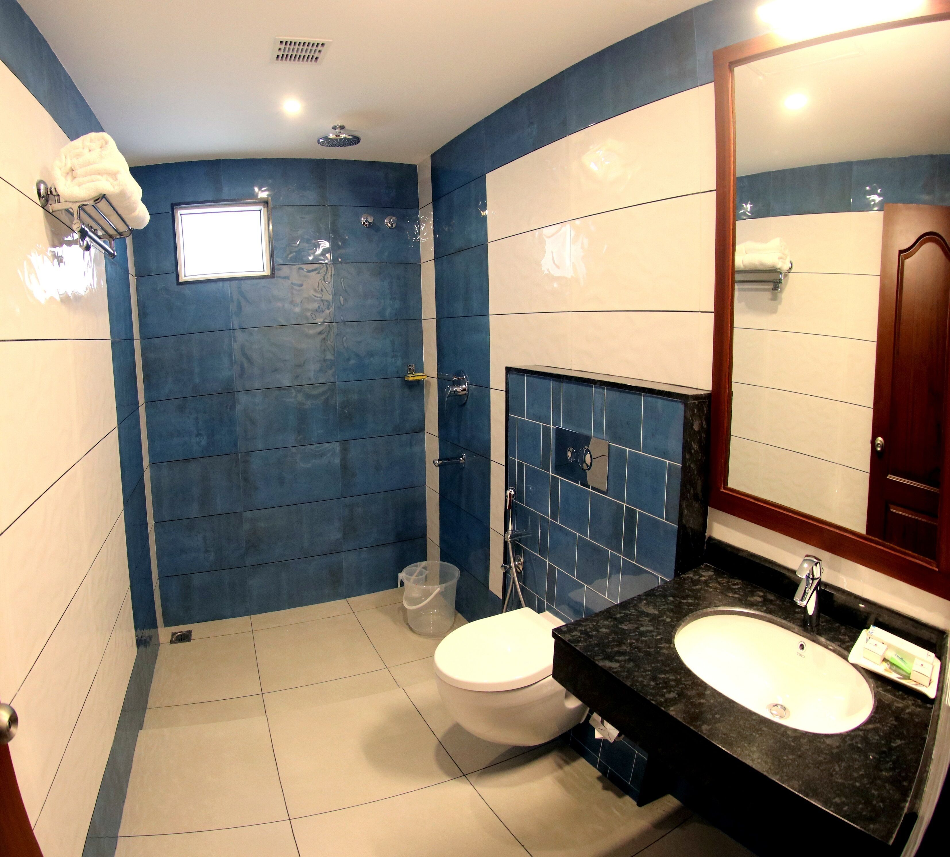 Un baño con inodoro blanco, lavamanos con encimera negra y espejo.