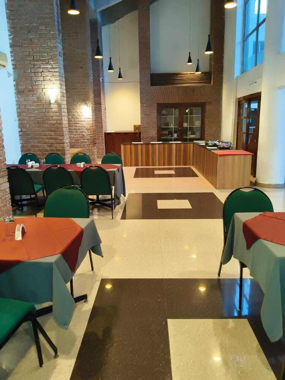 Un ristorante con soffitti alti, pareti in mattoni a vista e un bancone centrale. I tavoli sono disposti intorno al bancone, con lampade a sospensione.
