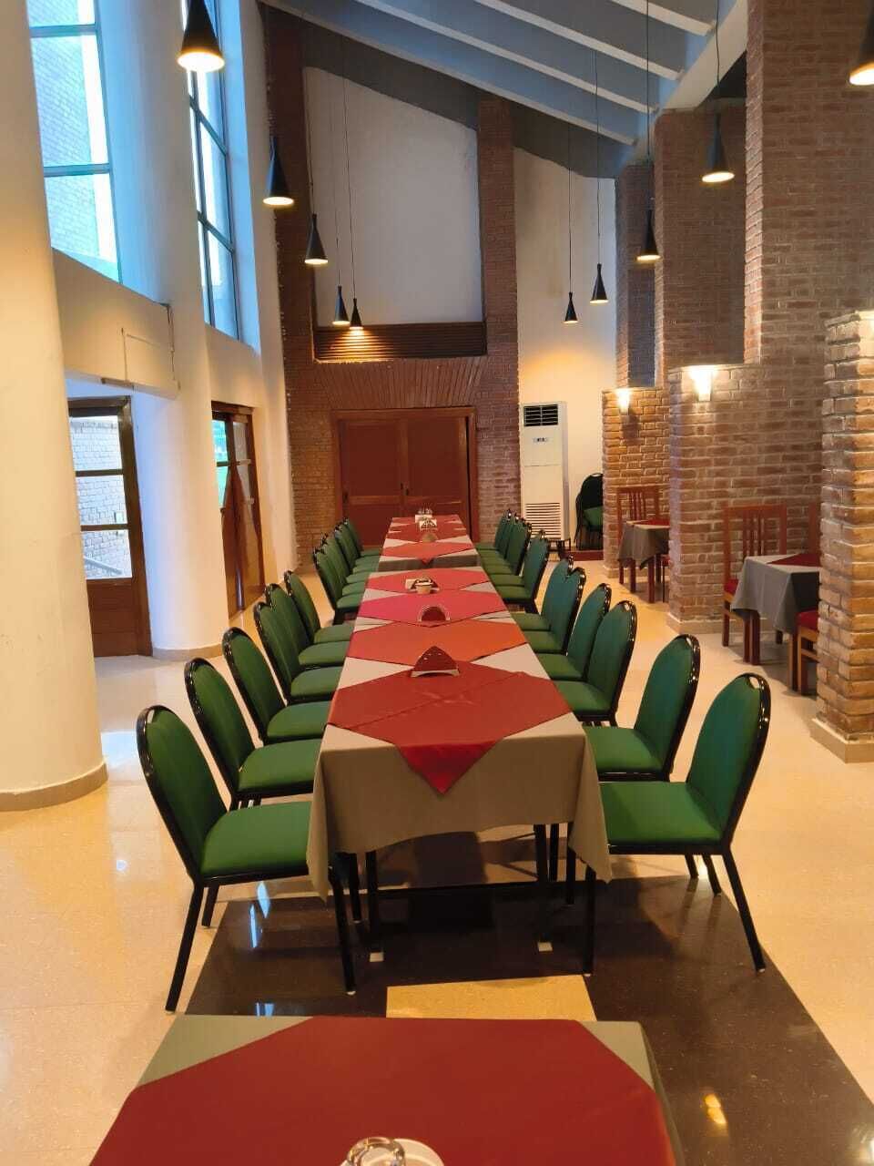 A conference room with a long table, green chairs, and pendant lighting.