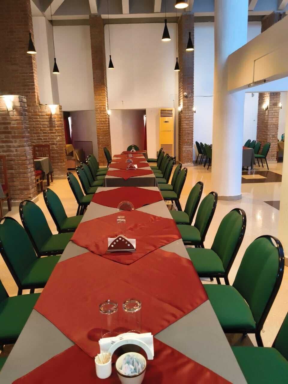 A conference room with a long table, green chairs, and a brick wall.