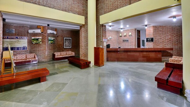 Un vestíbulo de hotel con una recepción, dos sofás estampados, un banco de madera y un mapa en la pared.