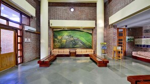 Un vestíbulo con un gran mural, bancos y un mostrador de recepción de madera.