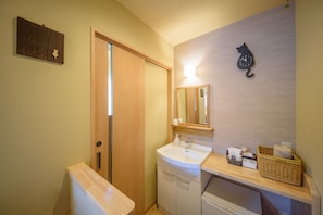 Ein Badezimmer mit Holztür, Waschbecken und Spiegel sowie einer an der Wand befestigten Uhr.