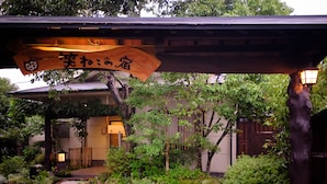 A traditional Japanese building with a wooden sign above the entrance. - Yufuin Waraneko no Yado (Yufu)