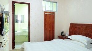 Slaapkamer met houten hoofdbord, een enkel bed, nachtkastje met telefoon en beker, en een raam boven de deur.