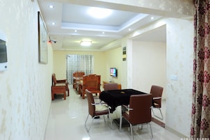 A dining area with a table and chairs, a television, and a patterned wall.