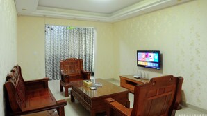 Een vergaderruimte met een houten tafel, stoelen, een televisie en een gordijn.