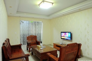 A conference room with a wooden table, chairs, a television, and a curtain.